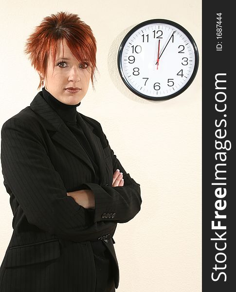 Thrity something business woman standing in front of clock on wall. Thrity something business woman standing in front of clock on wall.