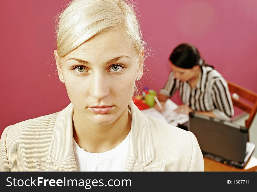 Businesswoman and a secretary over some paperwork in modern office-on pink