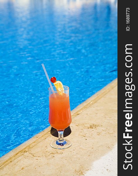 Cocktail stands on edge of pool. as a symbol of a rest.
