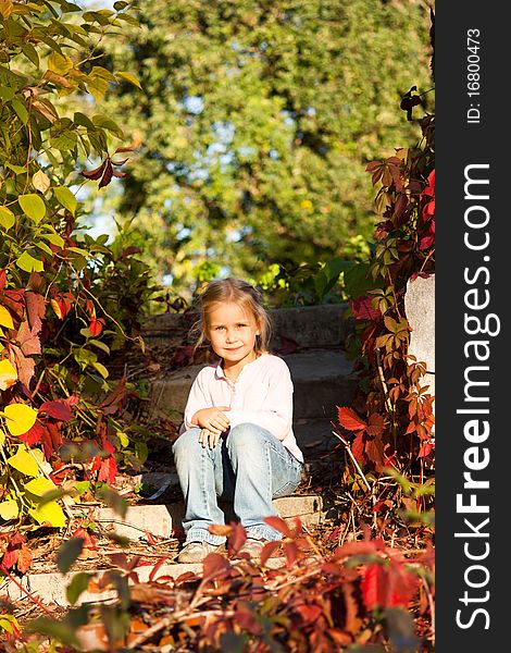 Beautiful girl sitting on a brick stairs in summer