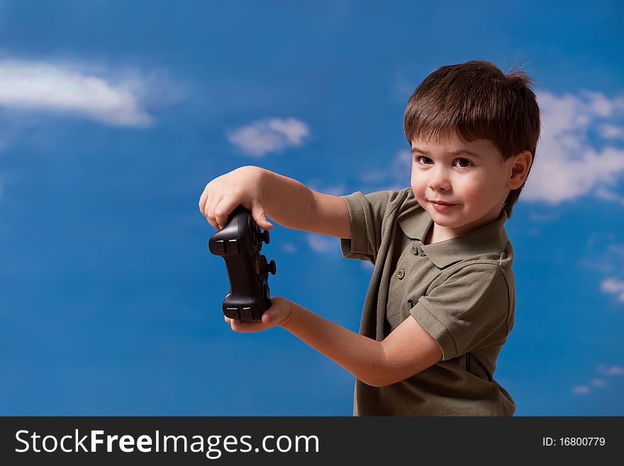 Cute three year old boy having fun with joystick in the hands on blue sky background. Cute three year old boy having fun with joystick in the hands on blue sky background