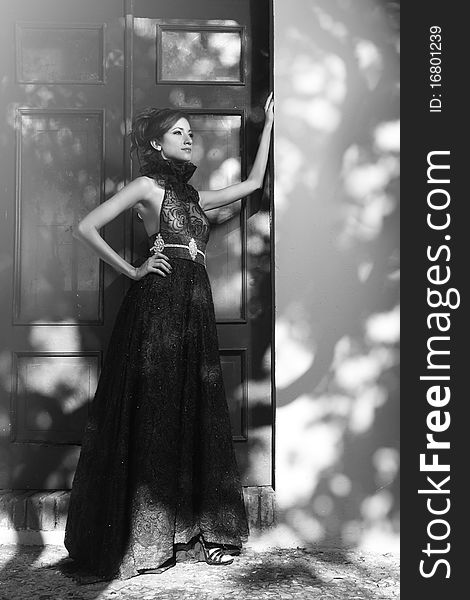 Black and white photo of a Model pose in front of a door. In the wall can see the shadows of a tree. Black and white photo of a Model pose in front of a door. In the wall can see the shadows of a tree.