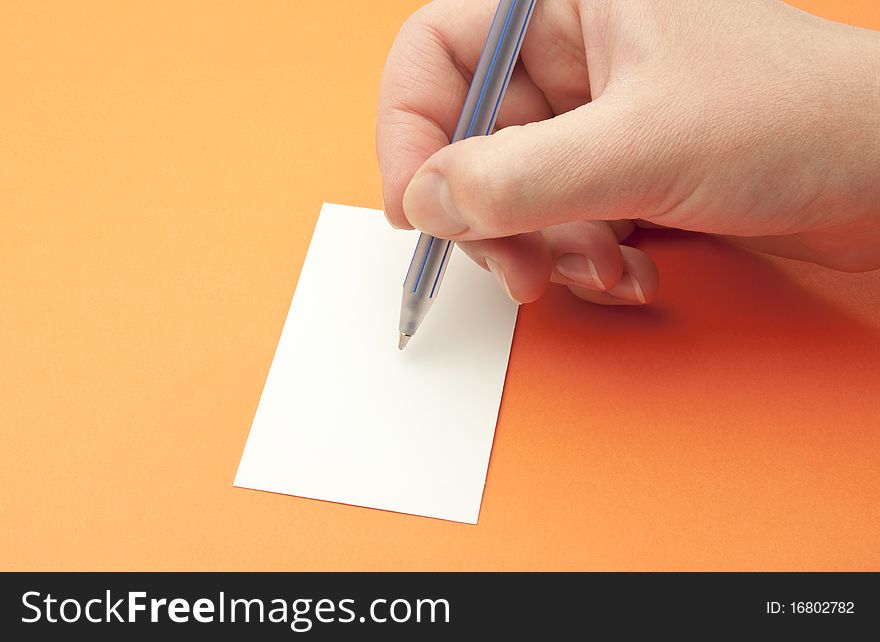 female hand with a pen on an orange background