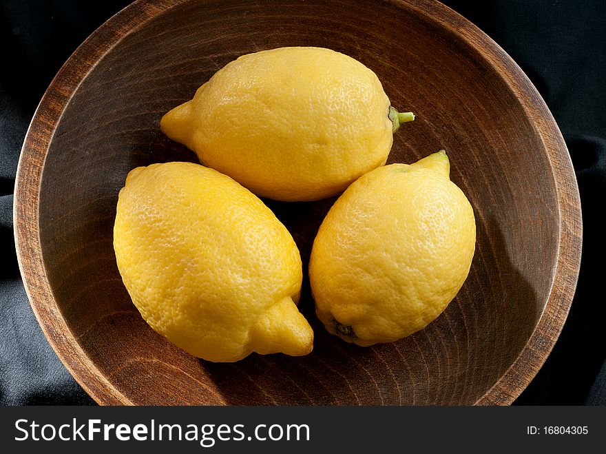 Three lemons in a wooden bowl