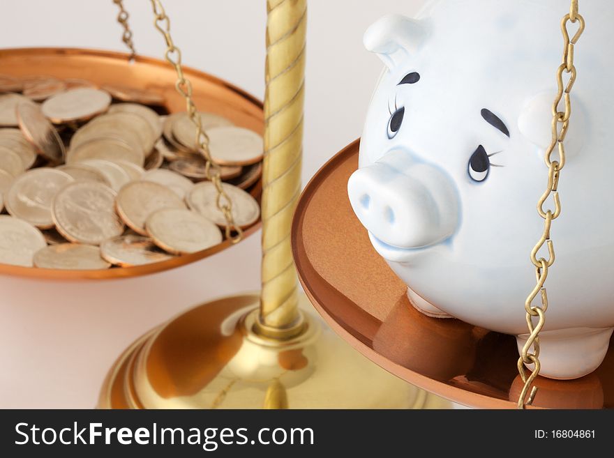 A Blue Piggy Bank adn Gold Coins on a Brass & Copper Colored Balance Scale. A Blue Piggy Bank adn Gold Coins on a Brass & Copper Colored Balance Scale