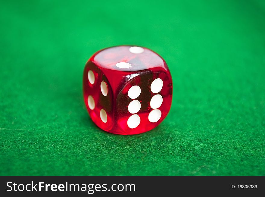 Single red dice on green background