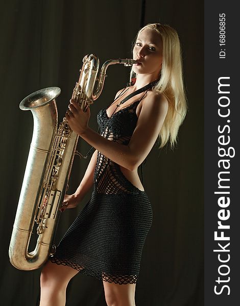The beautiful girl plays a saxophone. The beautiful girl plays a saxophone