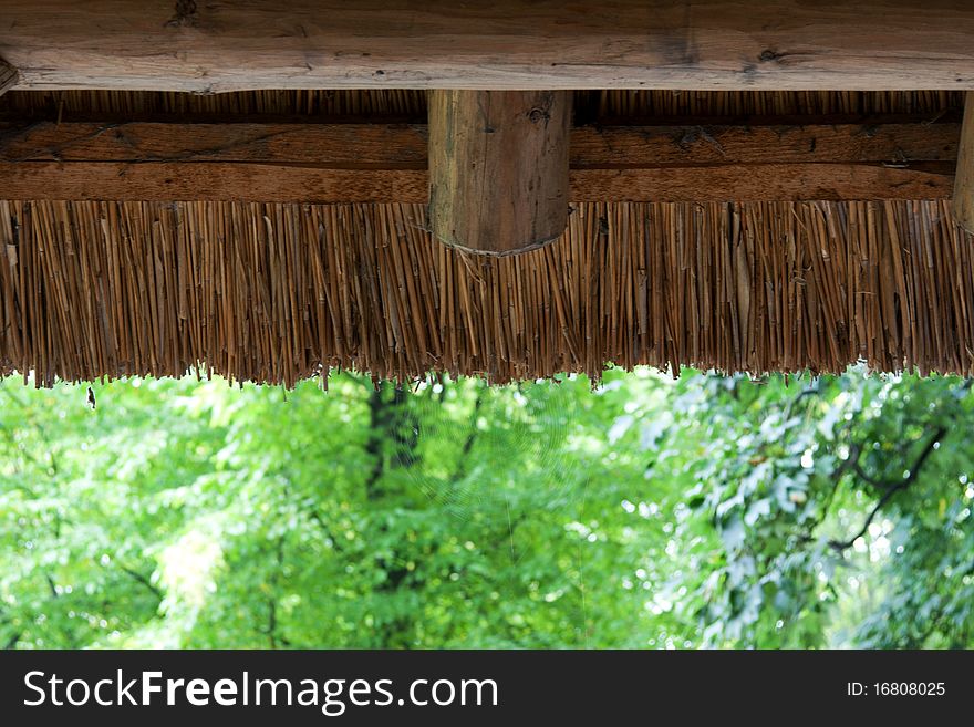 Reedy roof with wooden log on background green wood