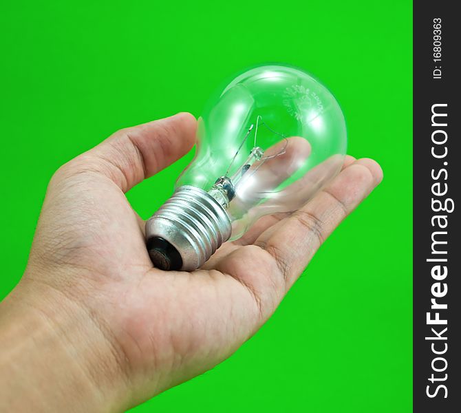 Lightbulb in a hand isolated on green background. Lightbulb in a hand isolated on green background.