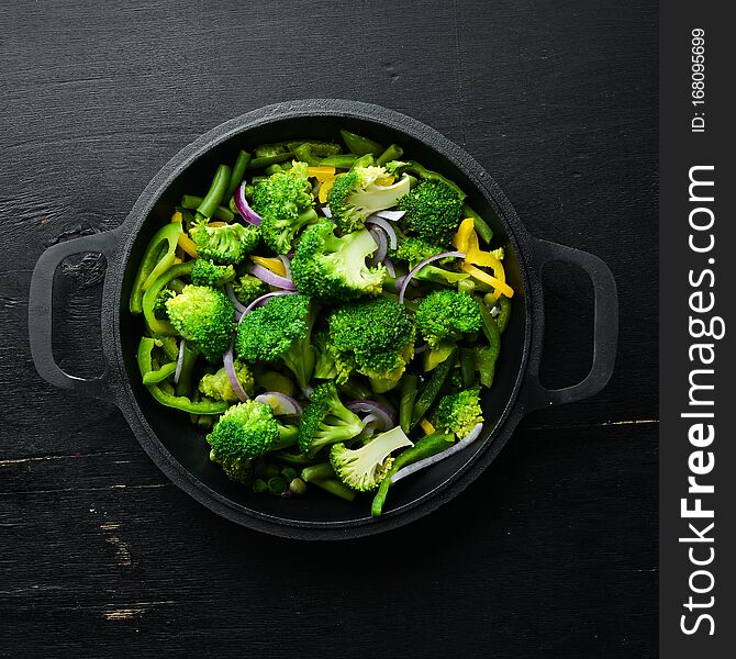 Green vegetables stewed in a frying pan. Broccoli, beans, green peas. Top view. Free space for your text