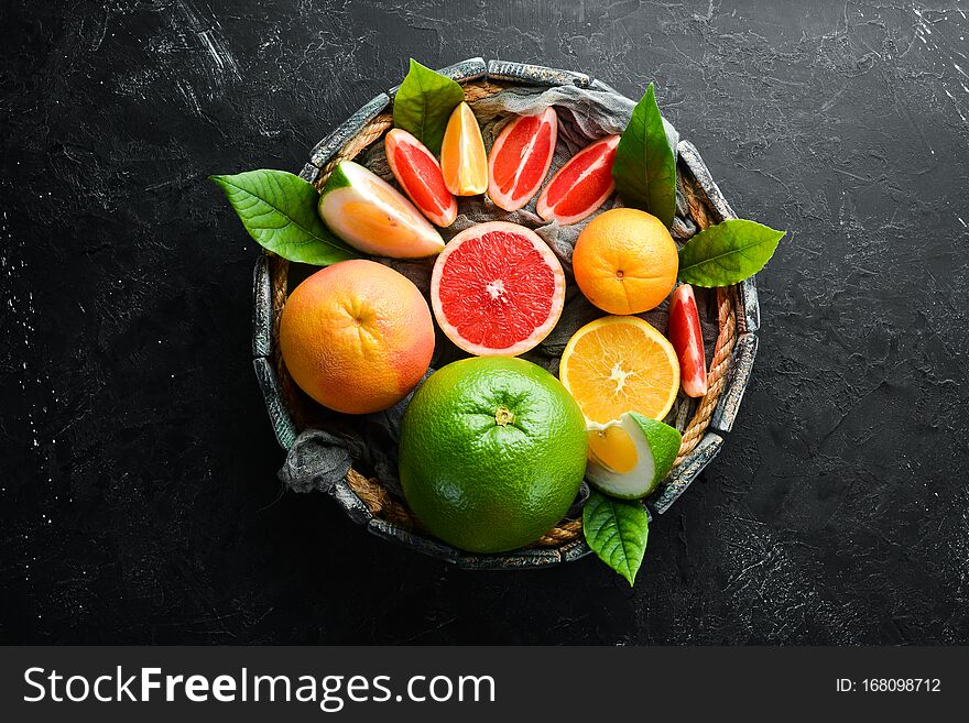 Fresh citrus fruits on black stone background. Top view. Free copy space