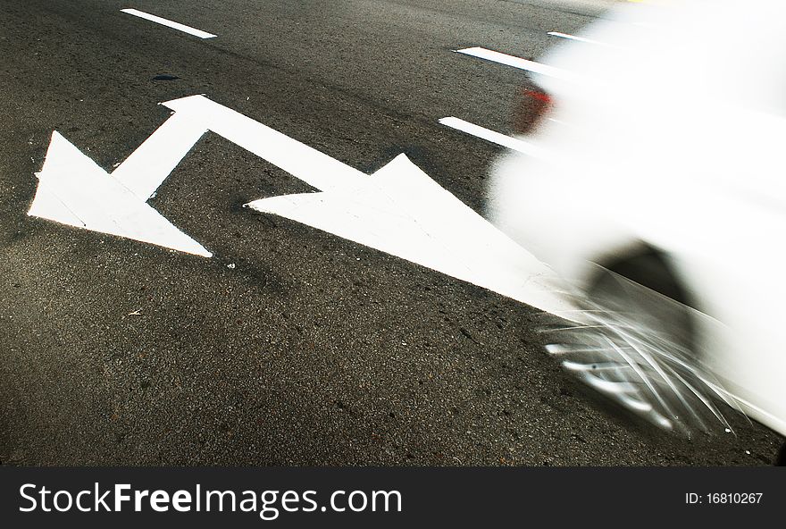 White arrow sign painted on pavement with blur white car. White arrow sign painted on pavement with blur white car