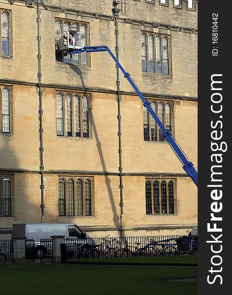 Window cleaner working on windows in collage building in Oxford, Oxfordshire, England. Window cleaner working on windows in collage building in Oxford, Oxfordshire, England.