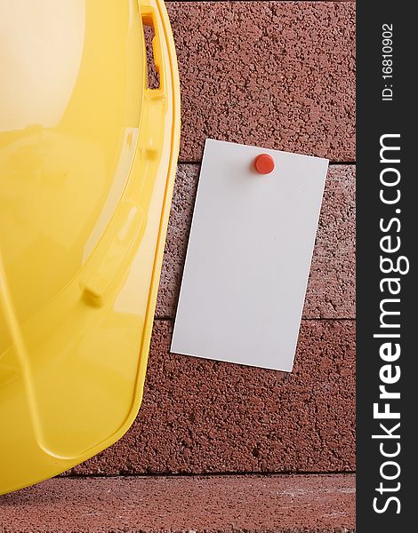 White piece of paper next to a yellow hard hat. Add your text to the paper. White piece of paper next to a yellow hard hat. Add your text to the paper.