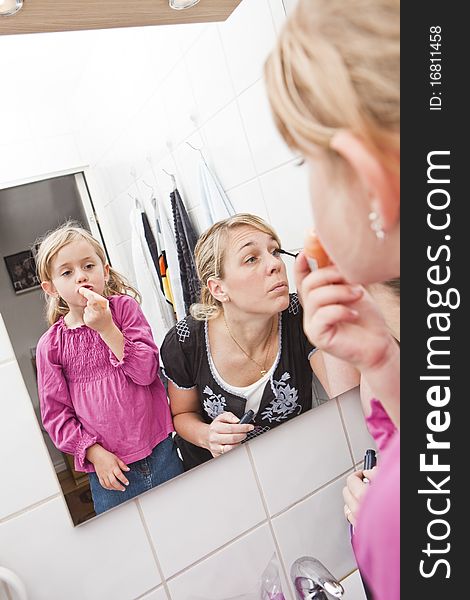 Mother and Daughter put on make-up in the bathroom