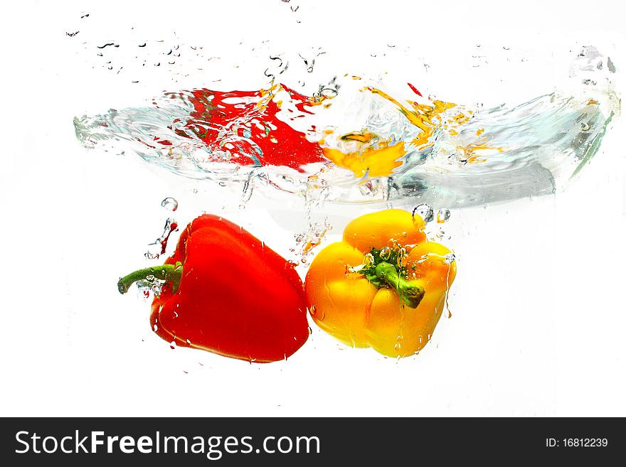 Red and yellow peppers into water over white