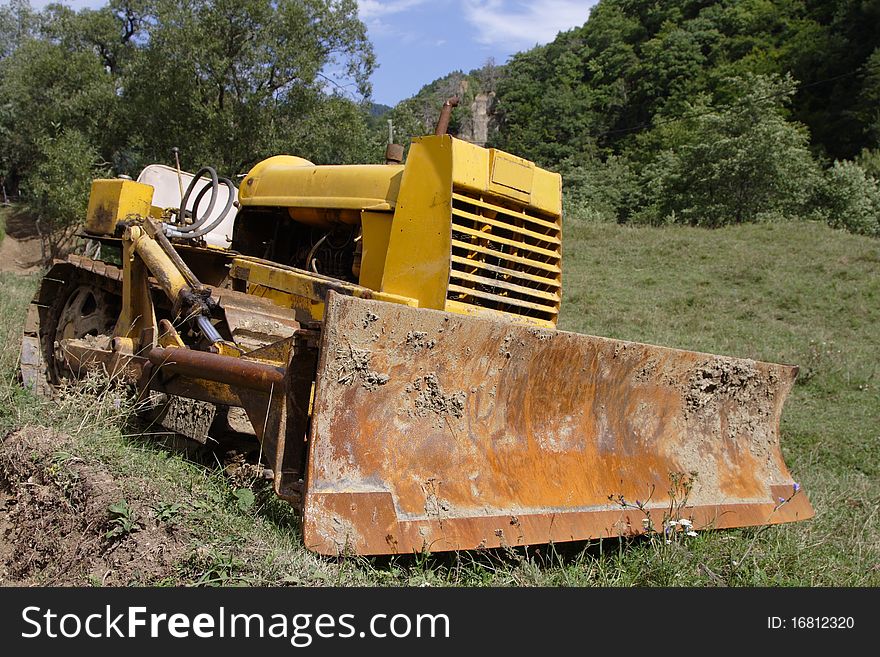 Old bulldozer waiting for work. It is located near an old village, deep into the Carpathians mountains