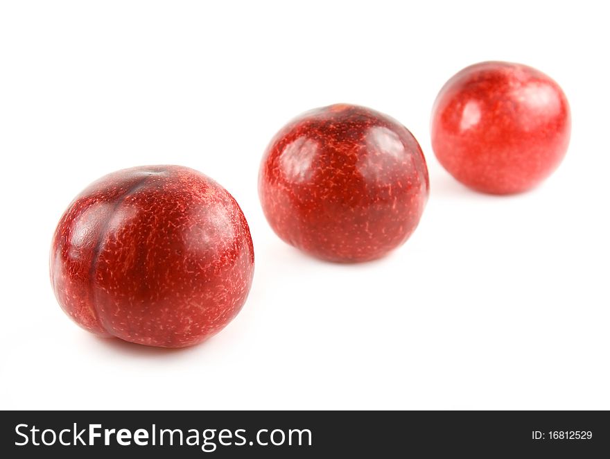 Three red plums isolated on white