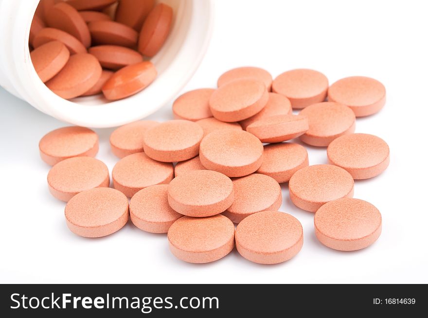 Close-up of orange pills with bottle, isolated on white, selective focus. Close-up of orange pills with bottle, isolated on white, selective focus.