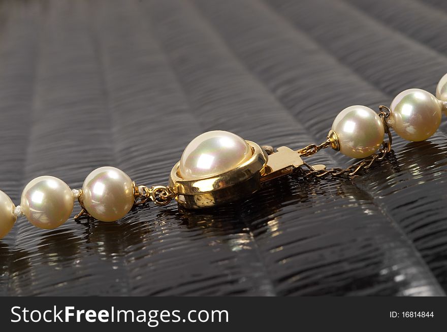 Pearl necklace fragment over black glossy background macro shot