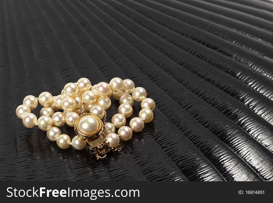 Pearl necklace over black glossy background macro shot