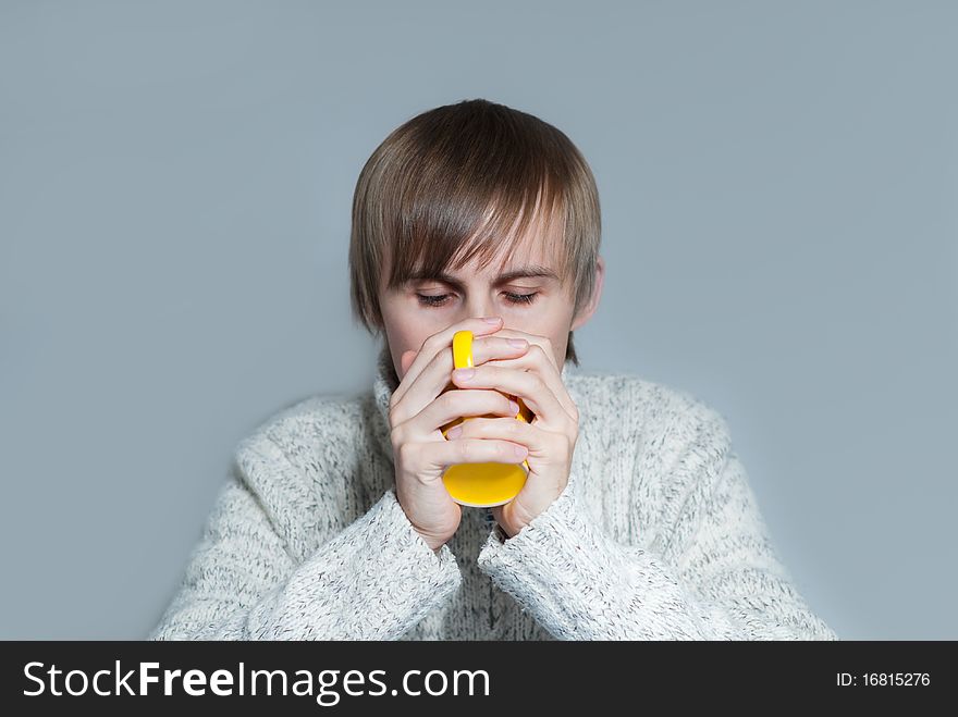 Young man drinking a hot tea from yellow cup