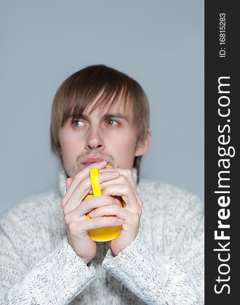Young man holding a hot tea in yellow cup. Young man holding a hot tea in yellow cup