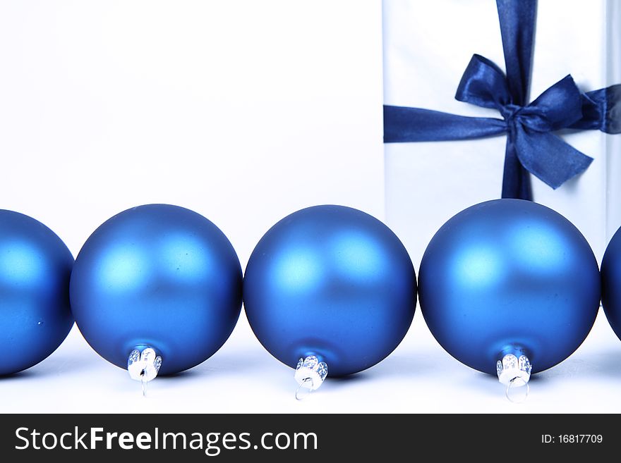 Blue matt christmas balls and a gift in silver wrapping on white background, with space for your text. Blue matt christmas balls and a gift in silver wrapping on white background, with space for your text