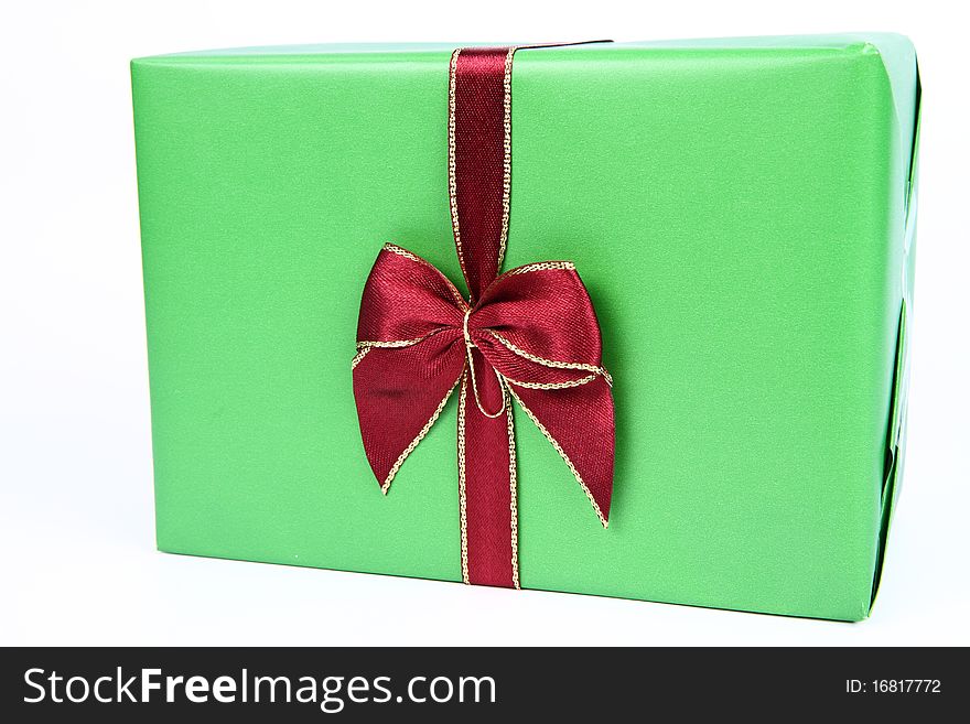 Gift in green wrapping with a red bow on white background