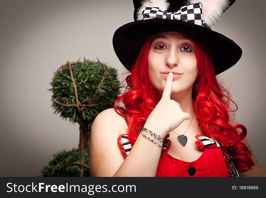 Attractive Red Haired Woman Wearing Bunny Ear Hat on a Grey Background.