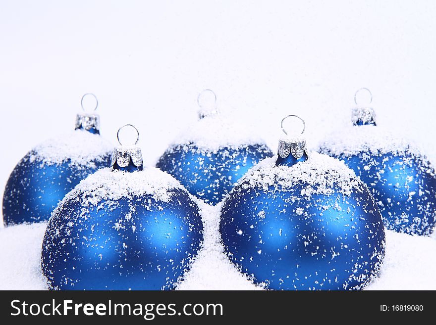 Blue matt christmas balls on snow and with snow falling on white background. Blue matt christmas balls on snow and with snow falling on white background