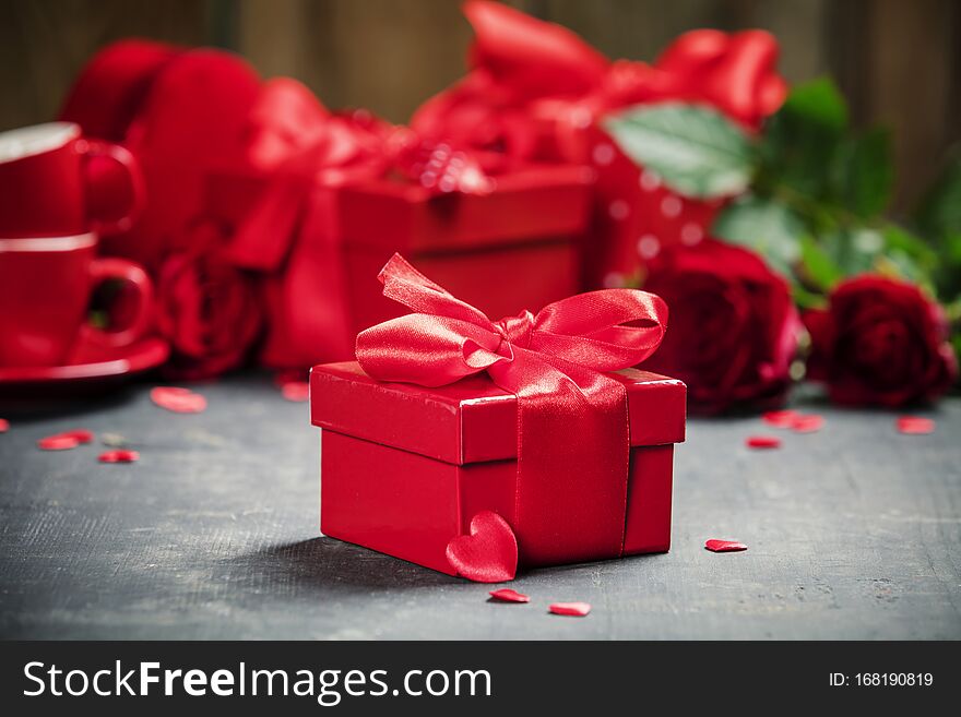 Valentine`s Day concept. Gift with red bow on the wooden background. Valentines gift boxes tied with a red satin ribbon bow and beautiful roses on rustic background. Valentine`s Day concept. Gift with red bow on the wooden background. Valentines gift boxes tied with a red satin ribbon bow and beautiful roses on rustic background.