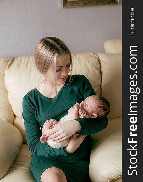 Young beautiful blond hair mamaso with a baby in her arms at home. Happy motherhood