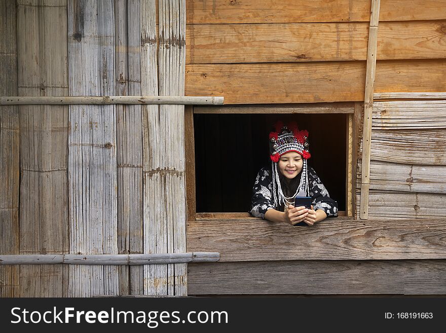 Tourists wearing hill tribe clothes. An Akha on the window. Tourists wearing Hmong hill tribe clothes and sitting with mobile, by
