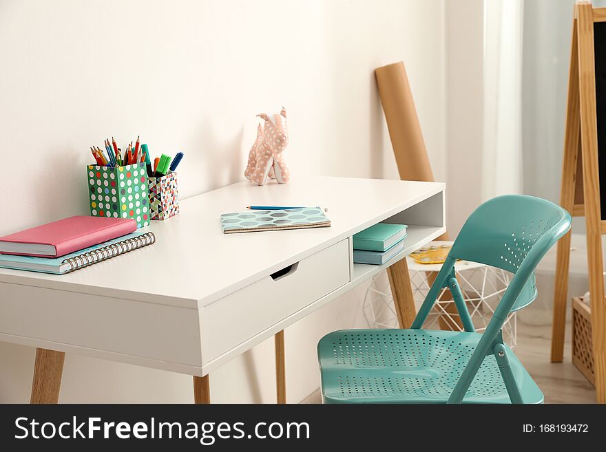 Table with chair near white wall in child room