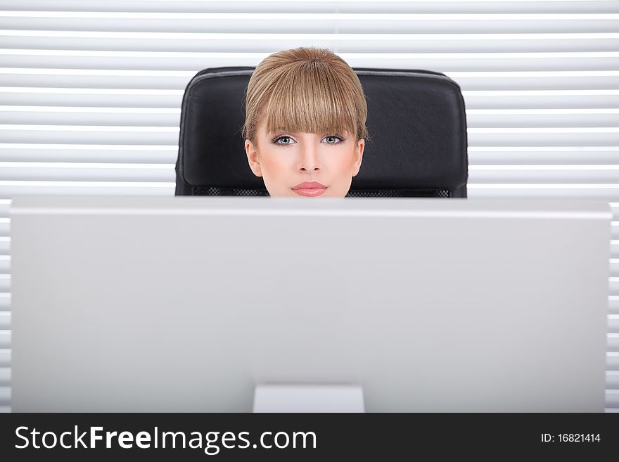 Businesswoman in her office looking over the monitor. Businesswoman in her office looking over the monitor