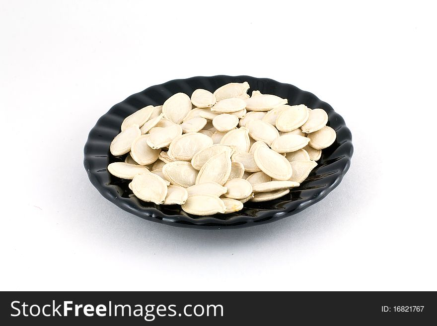 Pumpkin seeds on a glass plate isolated on white background