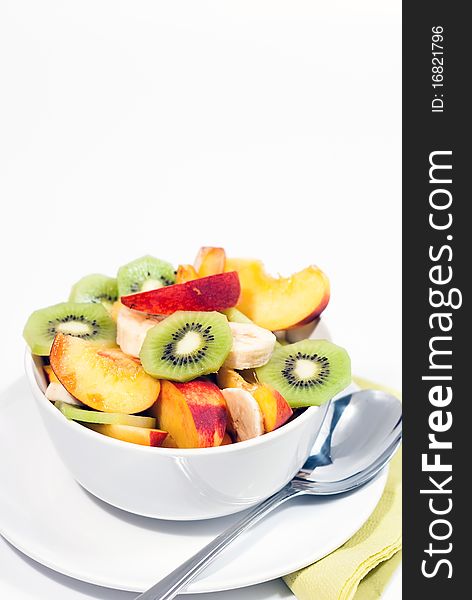 White bowl of fresh fruits and a spoon. White bowl of fresh fruits and a spoon