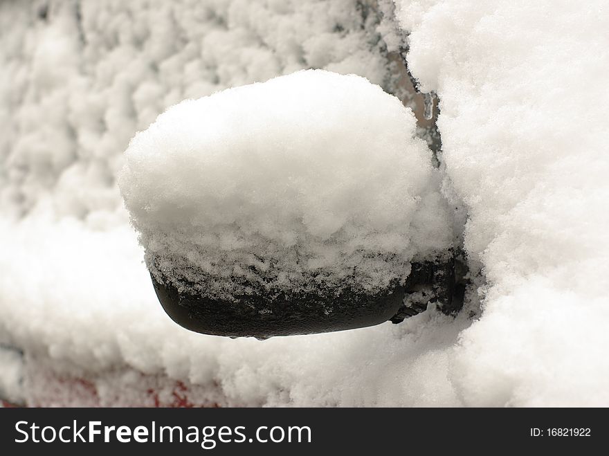 Car mirror covered with snow and ice