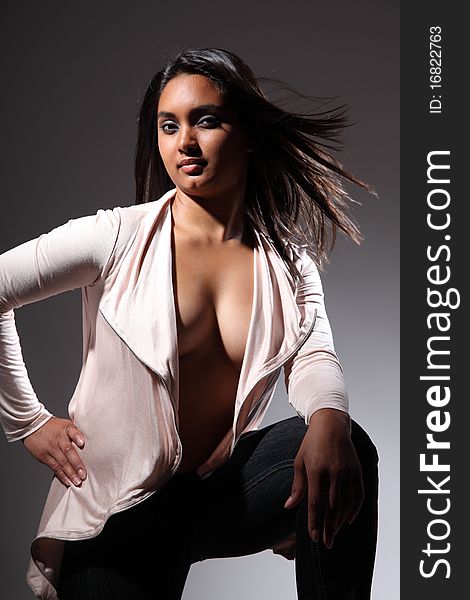 Beautiful and young fashion model in a kneeling pose, gazing straight into camera with hair catching in the wind. Wearing open front long sleeve shirt top showing voluptuous clevage. Beautiful and young fashion model in a kneeling pose, gazing straight into camera with hair catching in the wind. Wearing open front long sleeve shirt top showing voluptuous clevage.