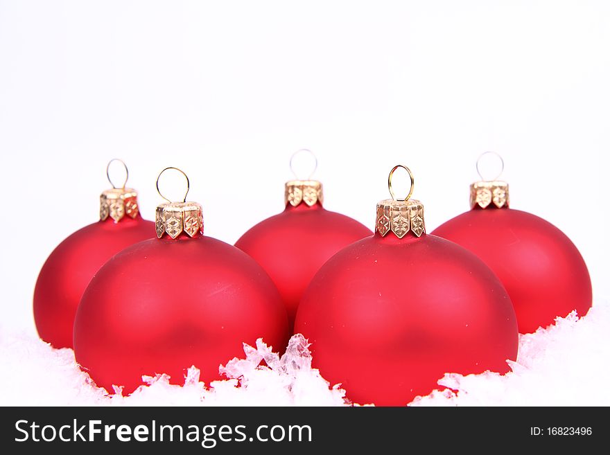 Red matt christmas balls on snow on white background, with space for your text