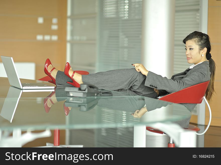 Relaxed Chinese businesswoman, shoes on her desk. Relaxed Chinese businesswoman, shoes on her desk