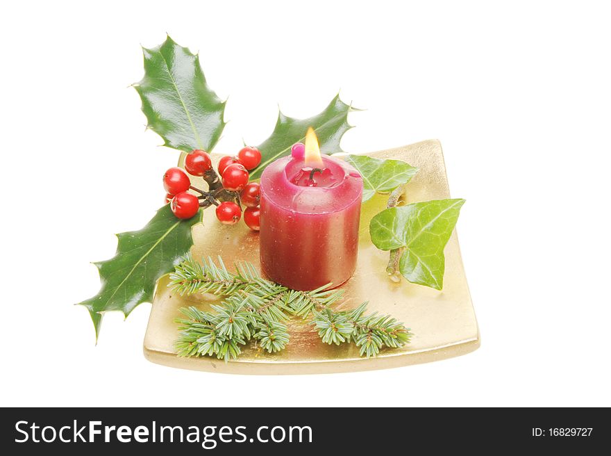 Christmas table decoration, a gold dish with a burning red candle surrounded by holly, ivy and pine needles