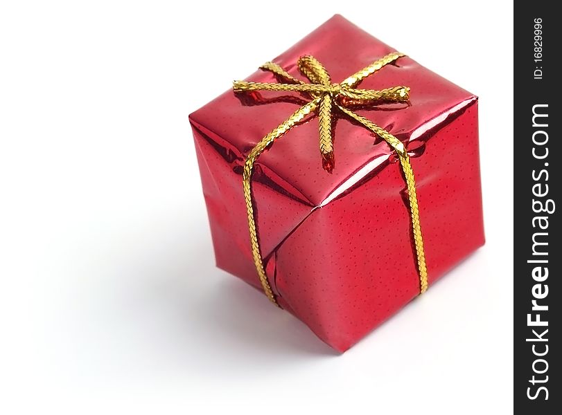A red box tied with a gold ribbon. A gift for Christmas, Birthday, Wedding, or Valentine's day. Soft focus view.