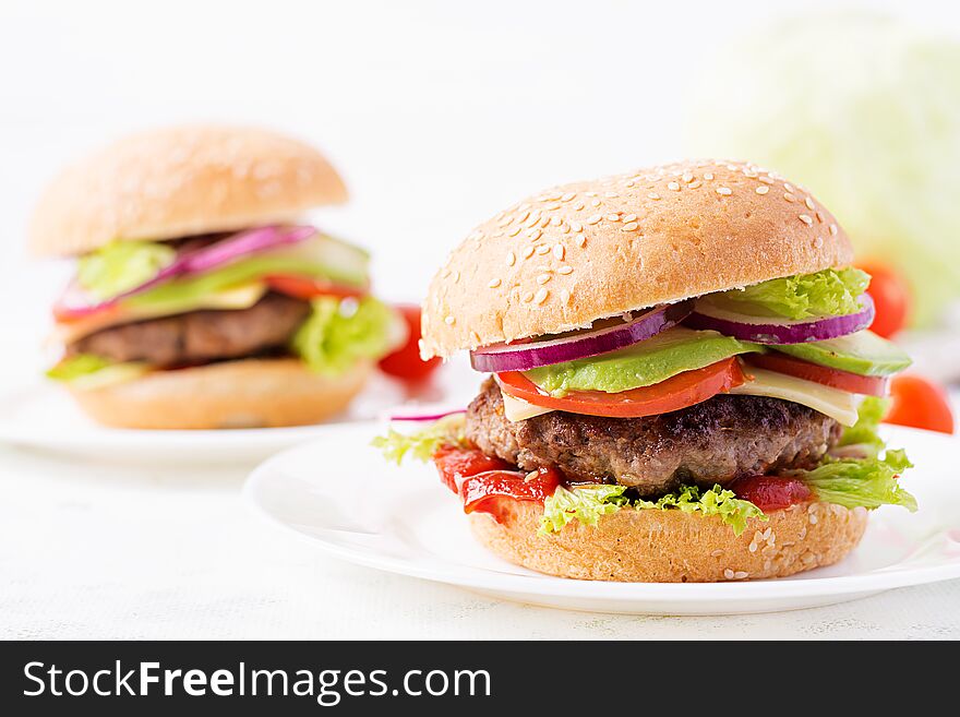 Big sandwich - hamburger burger with beef, avocado, tomato and red onions on light background. American cuisine. Fast Food