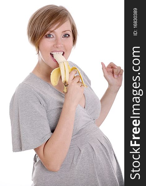 Young pregnant woman eating banana