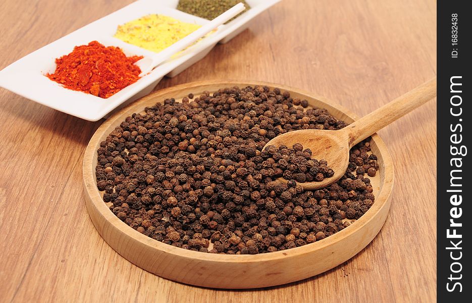 Peppercorns on the table in a wooden bowl. Peppercorns on the table in a wooden bowl