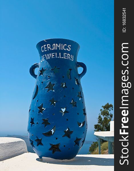 Big blue ceramic vase with decoration of stars, moons and a heart. Vase is standing on a white terrace on beautiful island of Santorini, Greece. As always in this hot country is clear blue sky. Big blue ceramic vase with decoration of stars, moons and a heart. Vase is standing on a white terrace on beautiful island of Santorini, Greece. As always in this hot country is clear blue sky.