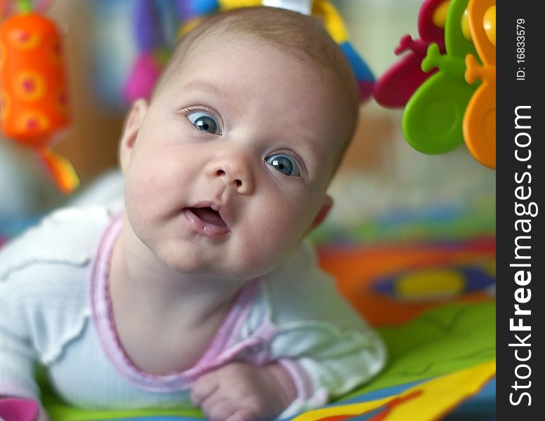 Beautiful baby with toys. She looks an amazed look.