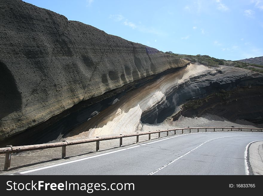 Ash deposits layered over time as different volcanic eruptions took place in the Canary Islands, Tenerife (Teide is the volcano that is responsable for that).